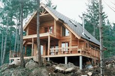 a small wooden cabin in the woods with porches and stairs leading up to it