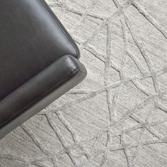 a black leather chair sitting on top of a carpet covered in grey and white designs