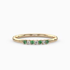 a yellow gold ring with three green and white stones on the side, in front of a