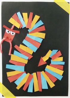 an art project made out of construction paper with scissors and tape on the side, in front of a black background