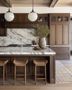 a large kitchen with marble counter tops and wooden stools in front of an island