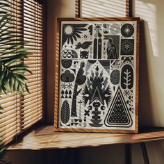 a wooden frame with black and white artwork on it next to a potted plant