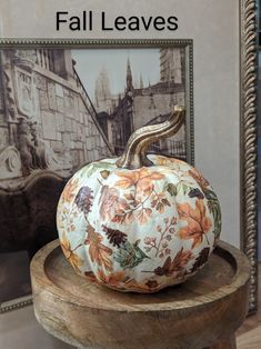 a white pumpkin sitting on top of a wooden stand in front of a framed photo