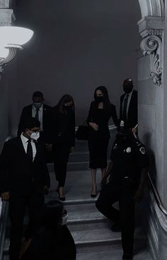 a group of people in suits and masks walking down stairs