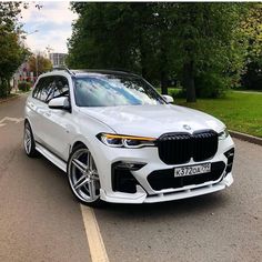 a white bmw suv is parked on the street