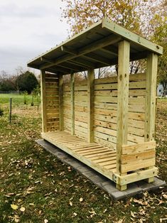 a small wooden shelter sitting on top of a lush green field