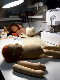 a stuffed doll laying on top of a table next to a sewing machine