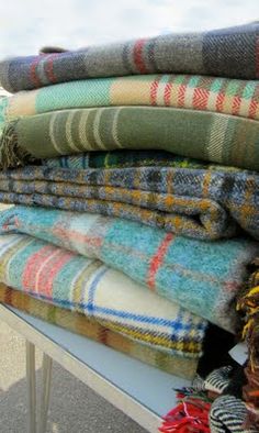 a pile of blankets sitting on top of a white table next to a blue sky