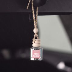 a small bottle hanging from the side of a black car with a rope attached to it