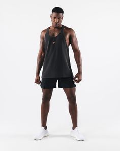 a man standing in front of a white background wearing black shorts and a tank top