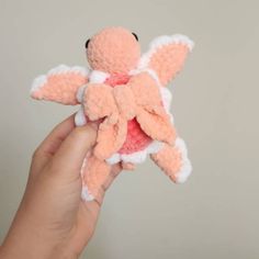 a hand holding an orange and white stuffed animal in it's right hand,