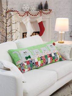 a white couch sitting in front of a fireplace with christmas stockings on the mantel