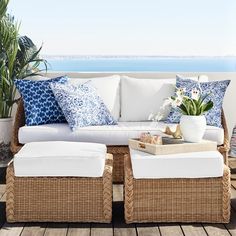 a white couch sitting on top of a wooden floor next to a potted plant