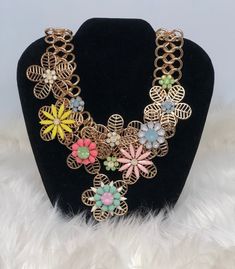 Statement Necklace with flower accents in various colors. Spring Flower Shaped Jewelry With 3d Flowers, Spring Chic Jewelry With Flower Decoration, Chic Spring Jewelry With Flower Decoration, Handmade Flower-shaped Chic Jewelry, Spring Flower Jewelry With 3d Flowers, Metal Flower Charm Necklaces, Chic Spring Jewelry With Flower Charm, Trendy Multicolor Flower Shaped Jewelry, Trendy Flower Pendant Necklace With Charm