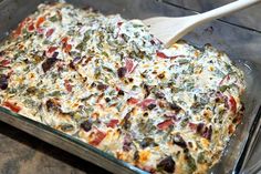 a casserole dish with spinach, cheese and other toppings in it