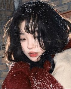 a woman with dark hair wearing a red coat in the snow