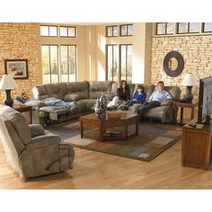 three people sitting on couches in a living room with wood floors and large windows