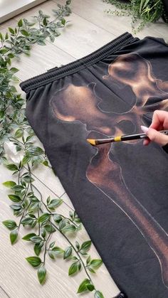 someone is using scissors to cut out an image on the side of a black skirt