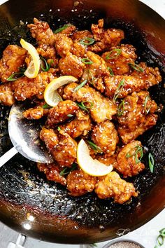 a pan filled with chicken and lemons on top of a table next to spices