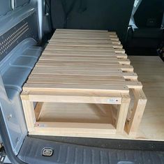 the back end of a truck with a wooden bench in it's trunk area