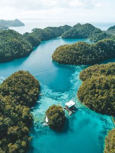 an aerial view of several small islands in the middle of blue water with trees around them