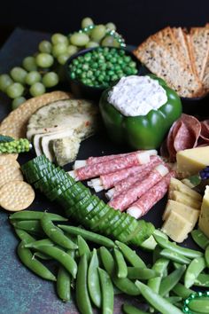 an assortment of cheeses, meats and vegetables on a plate with crackers