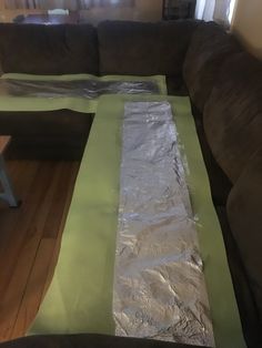 the couch is covered with plastic wrap and some wood flooring in front of it