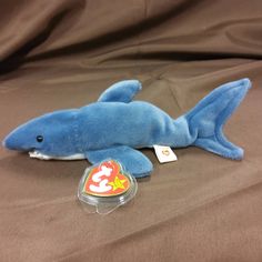 a blue shark stuffed animal laying on top of a bed next to a pacifier