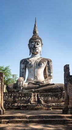 a large buddha statue sitting in the middle of a park