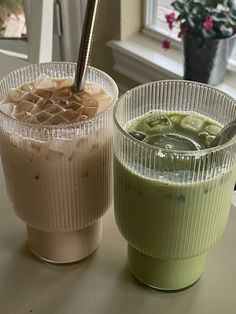 two cups filled with drinks sitting on top of a table next to eachother