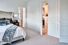 a bedroom with white walls and carpeted flooring has a large bed in it