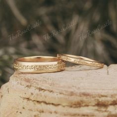 two gold wedding rings sitting on top of a rock