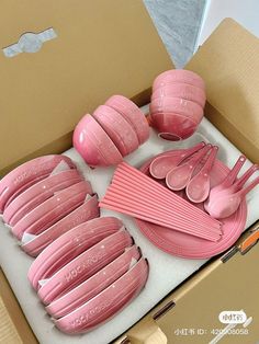 a box filled with pink plastic cups and spoons next to a cardboard box on top of a table