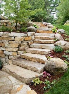 stone steps leading up to the top of a hill with flowers and trees in the background