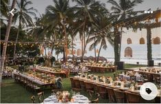 an outdoor dining area with palm trees and tables set up for a wedding reception at the beach