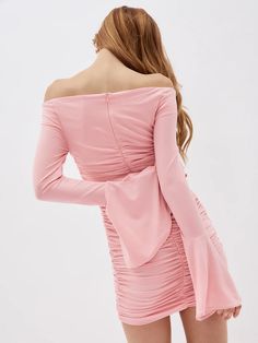 a woman wearing a pink dress with long sleeves and ruffles on the back