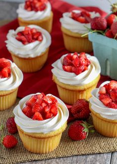 several cupcakes with white frosting and strawberries on the top are sitting on a mat