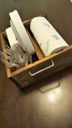 a wooden drawer with napkins and glassware in it on a wood table top