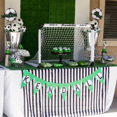 a table topped with soccer balls and cupcakes next to a goalie net