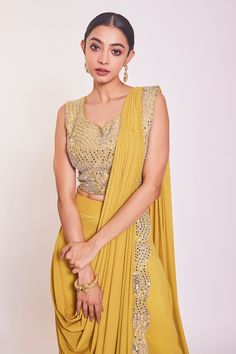 Yellow pre-draped saree with mirror and cutdana embroidery on the border. Comes with embroidered sleeveless blouse.
Component: 2
Pattern: Embroidery
Type Of Work: Mirror and Cutdana
Neckline: Leaf
Sleeve Type: Sleeveless
Fabric: Lycra
Color: Yellow
Other Details: 
Saree with scalloped border
Mirror and cutdana embroidered blouse
V neck back with dori
Occasion: Mehendi and Haldi - Aza Fashions Border Mirror, Shimmer Saree, Cutdana Embroidery, Yellow Mirror, Leaf Sleeve, Embroidery Mirror, Draped Saree, Scalloped Border, Drape Saree