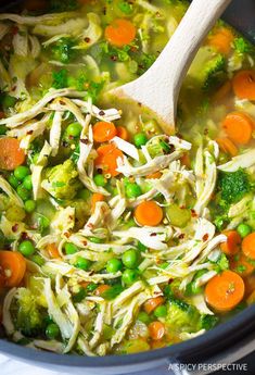 a wooden spoon in a slow cooker filled with chicken and veggie soup