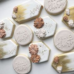 decorated cookies with frosting and flowers are arranged on a white tablecloth that says happy birthday