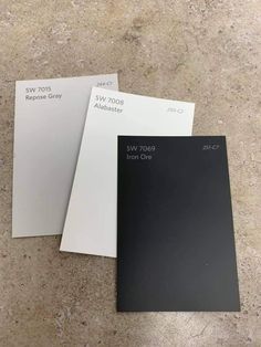 three different colors of paint sitting on top of a floor next to each other in a room