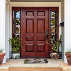 the front door to a house with two potted plants on either side and an entry mat that says hey yall