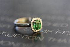 a close up of a ring with a green stone in the center on a black surface