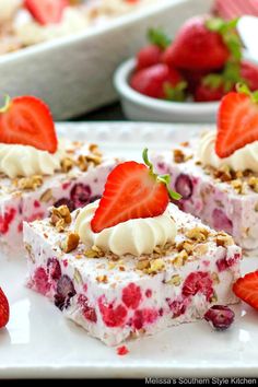 strawberry cheesecake bars with whipped cream and strawberries on the top are ready to be eaten