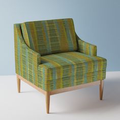 a green and yellow striped chair sitting on top of a white floor next to a blue wall