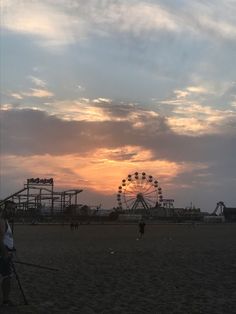 the sun is setting over an amusement park with ferris wheel and roller coasters in the background