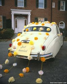 an old car is decorated with yellow and white flowers