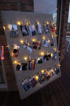 a bulletin board with pictures hanging on it and string lights strung from the pegs